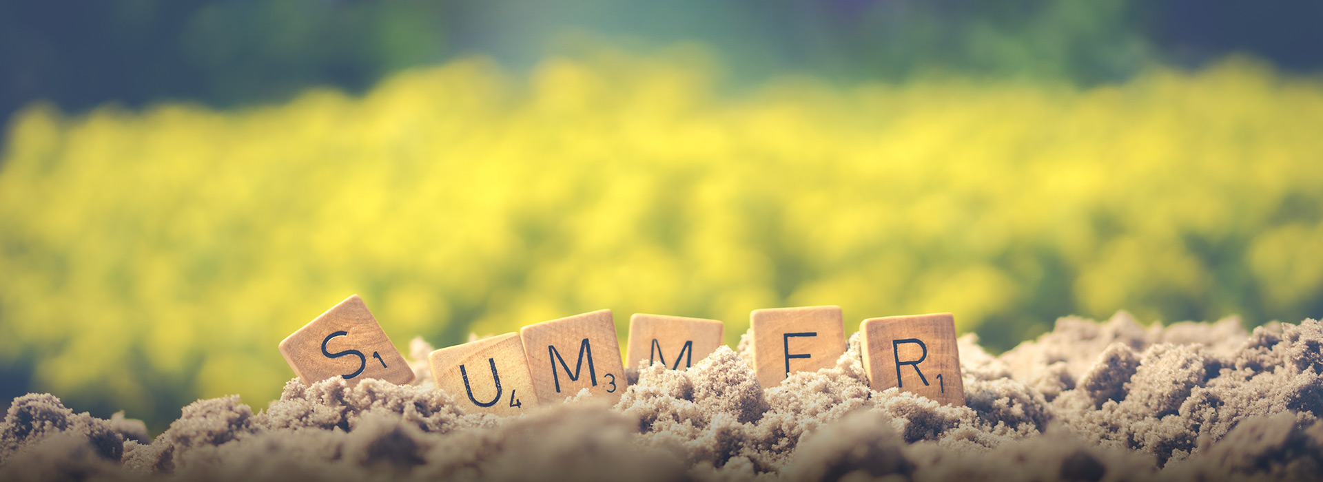 "Summer" written in Scrabble letters in the sand